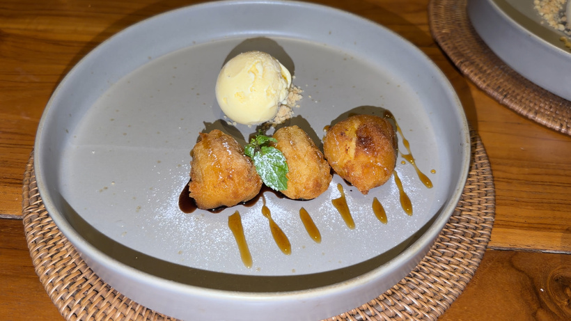 Banana fritters with a scoop of ice cream and caramel drizzle on a grey plate at Plantation restaurant