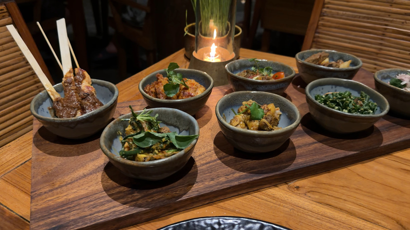Balinese Royal Rijsttafel at Alila Ubud: a tray of small bowls of local dishes and a satay skewer, lit by a candle
