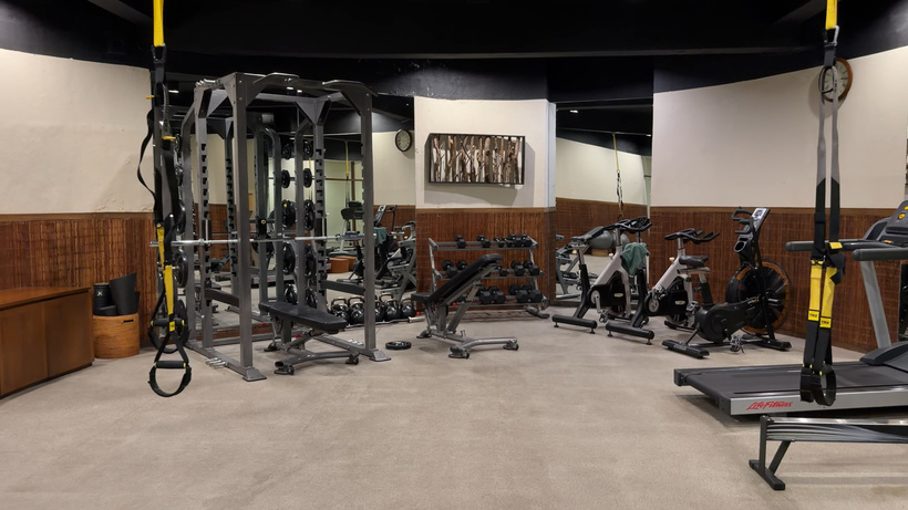 Gym at Alila Ubud with a weight rack, cable machine, exercise bikes, treadmill and suspension trainer straps