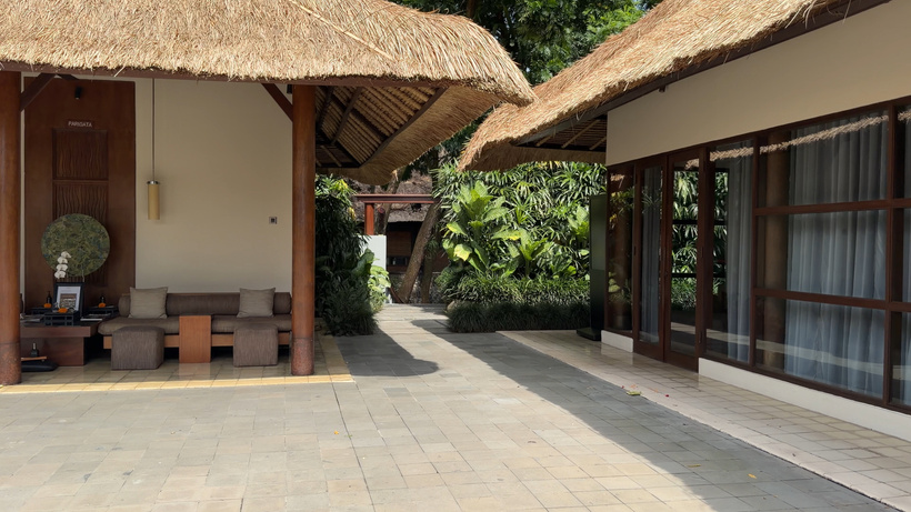 Thatched spa buildings around a paved courtyard with tropical plants and a small seating area at Spa Alila