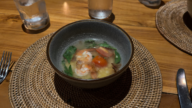 Bowl of soup with prawns and vegetables on a woven mat at Plantation restaurant, Alila Ubud