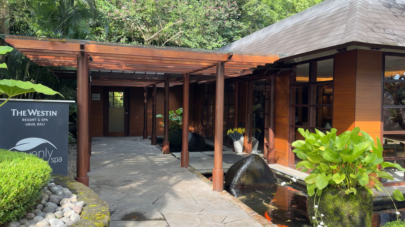 Covered wooden walkway leading to the Heavenly Spa by Westin, with a sign on the left and lush planting around.